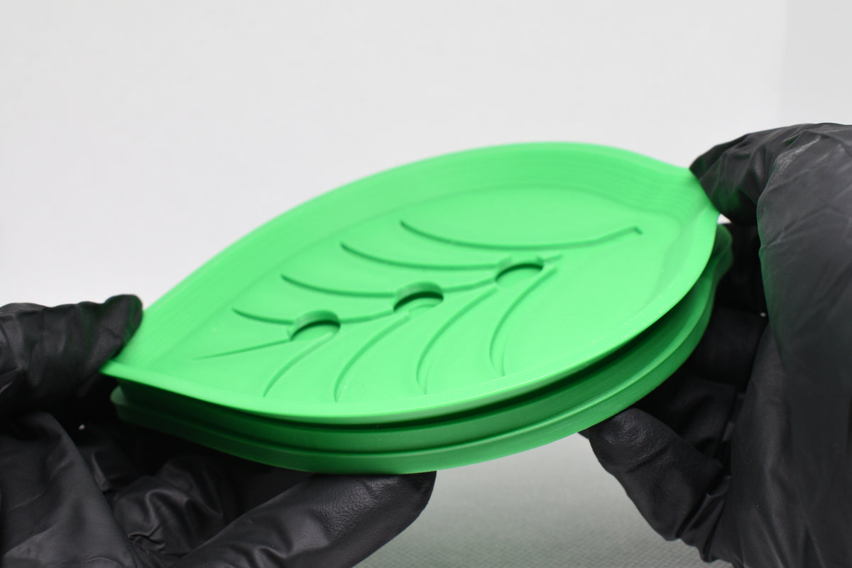 Hands in black gloves demonstrating two-piece removable drainage design of green leaf soap dish by LayerPlay Solara