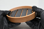 Hands in black gloves holding 3D printed two tone tan and black self-draining soap dish by LayerPlay Solara