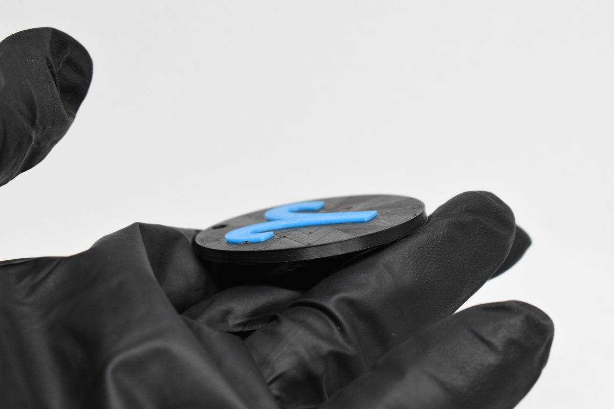 Side angle view showing raised 3D blue aries sign detail and thickness on black disc keychain by LayerPlay