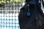 3D printed cancer zodiac keychain clipped to a black backpack zipper outdoors near a tennis court by LayerPlay