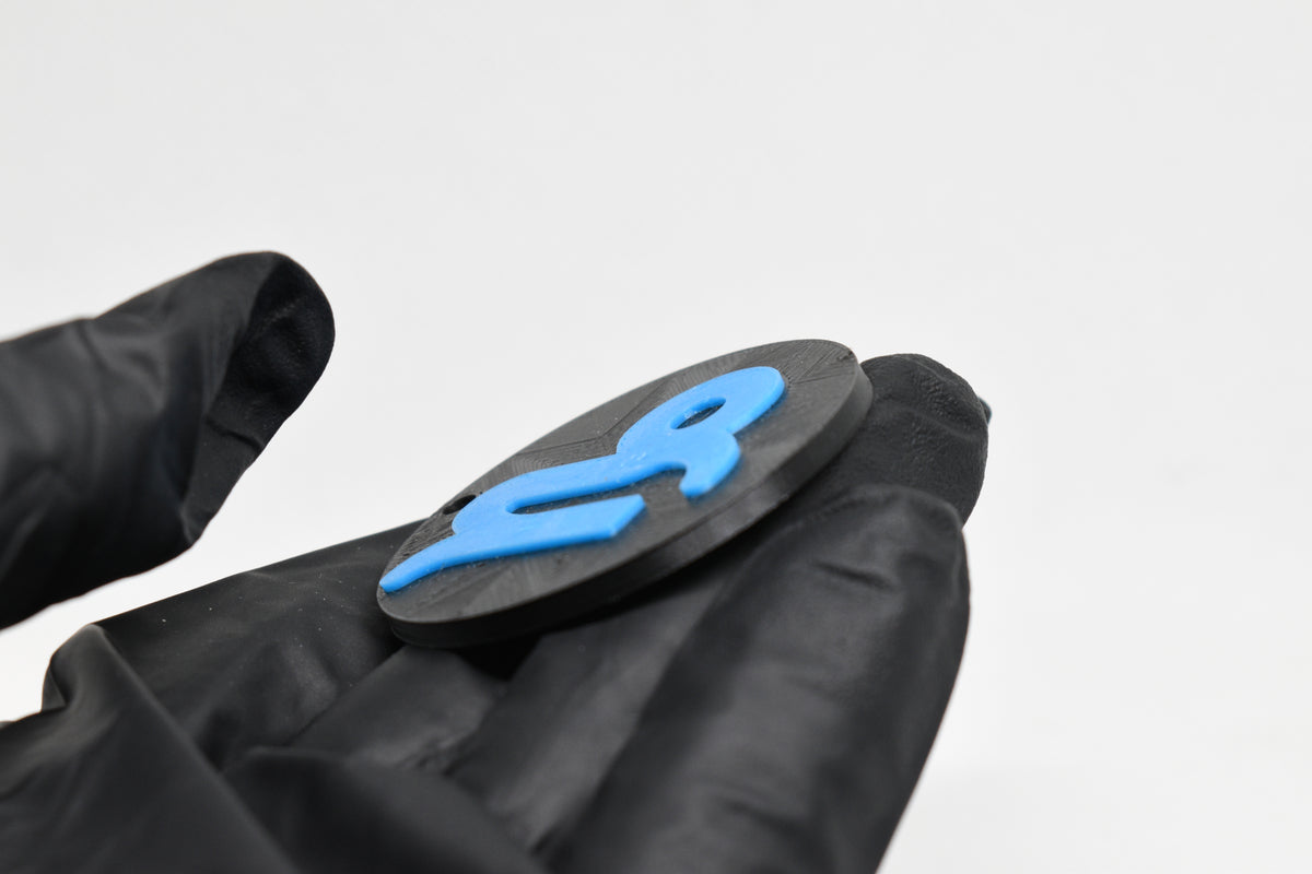 Side angle view showing raised 3D blue capricorn sign detail and thickness on black disc keychain by LayerPlay