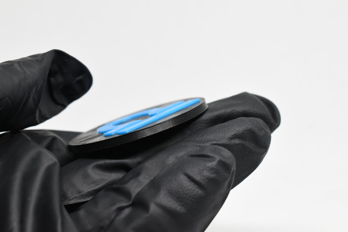 Side angle view showing raised 3D blue libra sign detail and thickness on black disc keychain by LayerPlay