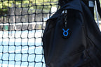3D printed taurus zodiac keychain clipped to a black backpack zipper outdoors near a tennis court by LayerPlay