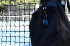 3D printed virgo zodiac keychain clipped to a black backpack zipper outdoors near a tennis court by LayerPlay