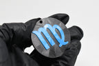 Hand in black glove holding 3D printed blue virgo zodiac symbol keychain front view detail by LayerPlay